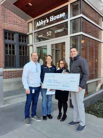 Gordon Lockbaum and AJ Andreoli from Sullivan Group present a check to employees of Abby's House.